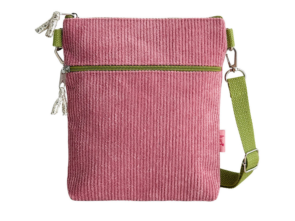 A pink corduroy crossbody bag with an olive green zipper and a matching green webbing strap, shown against a plain white background.