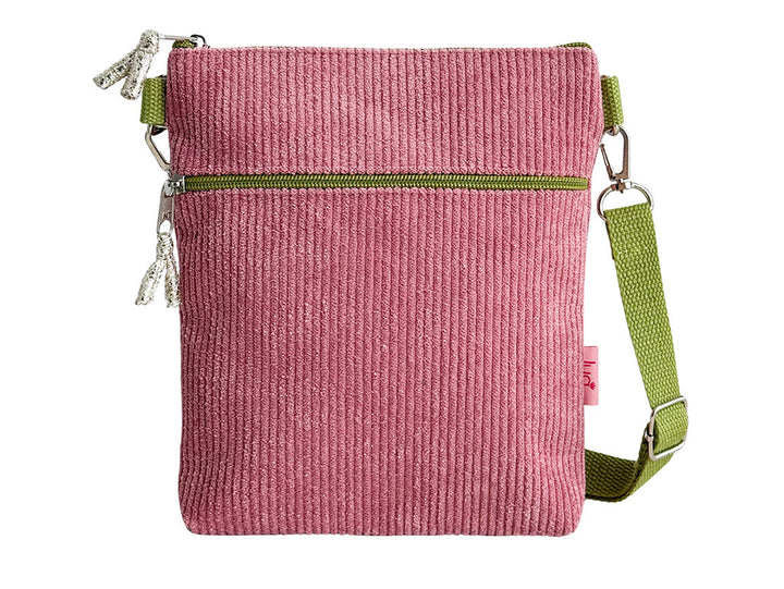 A pink corduroy crossbody bag with an olive green zipper and a matching green webbing strap, shown against a plain white background.