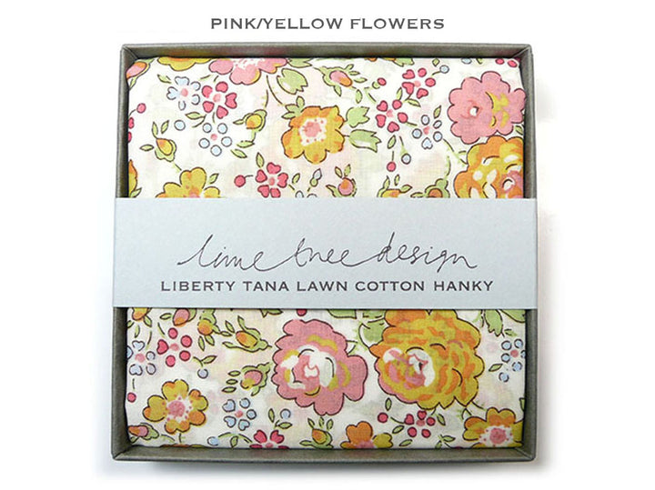 A folded cotton hanky with a pink and yellow floral print, presented in a gray box with a white paper band reading &
