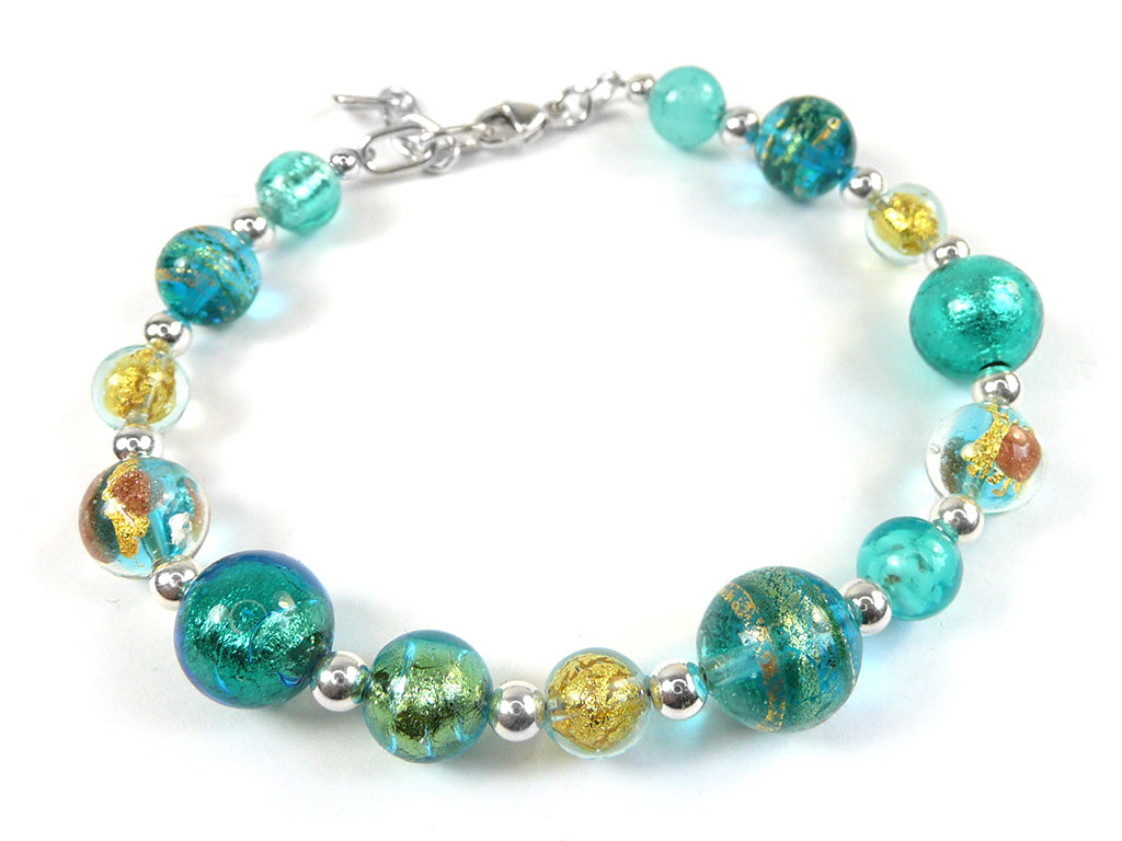 A beaded bracelet featuring translucent turquoise and teal glass beads with metallic gold leaf patterns, clear glass beads with gold flecks, and small silver spacer beads, completed with a silver lobster clasp on a white background.