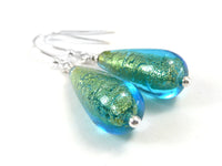 A pair of teardrop-shaped glass dangle earrings with shimmering green and blue glass beads, suspended from silver fishhook wires on a white background.