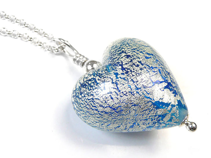 A heart-shaped glass pendant necklace with a textured blue and silver crackle pattern, hanging from a silver chain on a white background.