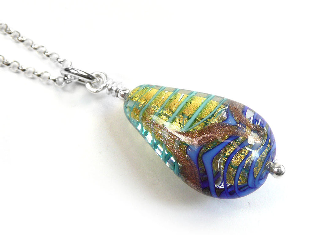 A teardrop-shaped glass pendant necklace on a silver chain, featuring a swirl pattern of blue, green, gold, and brown on a white background.