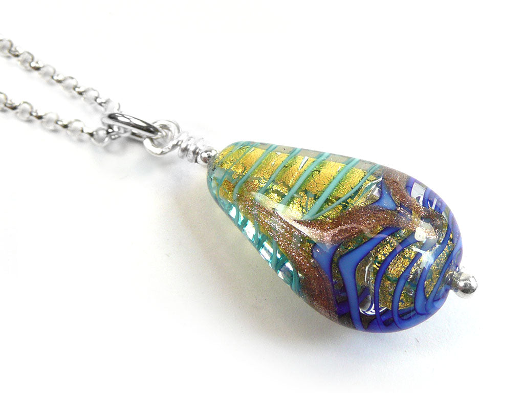 A teardrop-shaped glass pendant necklace on a silver chain, featuring a swirl pattern of blue, green, gold, and brown on a white background.