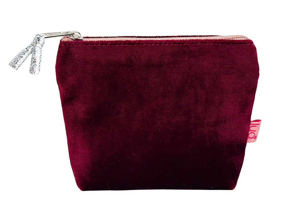 A burgundy velvet cosmetic pouch with a silver zipper and a small pink tag on the side, shown against a plain white background.