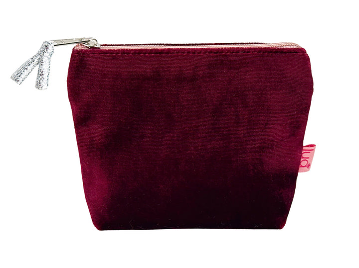 A burgundy velvet cosmetic pouch with a silver zipper and a small pink tag on the side, shown against a plain white background.