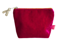 A small velvet pouch in a vibrant cerise pink colour, featuring a zipper and a silver glittery pull on the zip. A small pink fabric tag with the brand name 'Lua' is visible on the right side, set against a plain white background.