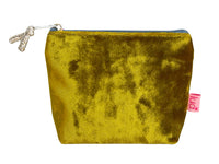 A small zippered velvet purse in olive-yellow velvet with a silver zipper pull and a pink 'Lua' brand tag on the side, shown against a plain white background.