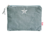 A dusty blue velvet pouch with a silver zipper, a silver embroidered star on the front, and a small pink tag on the side, shown against a plain white background.