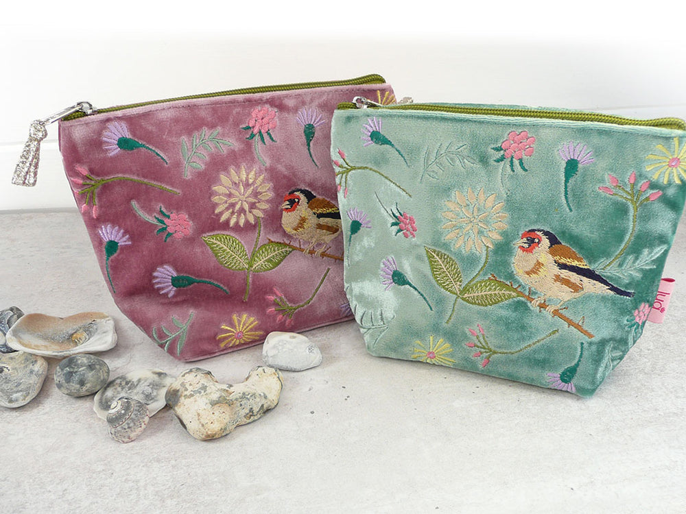 Two velvet zipped pouches with bird and floral embroidery on a light background