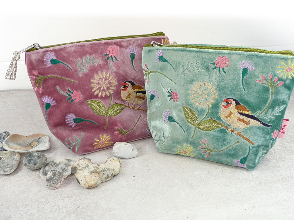 Two velvet zipped pouches with bird and floral embroidery on a light background