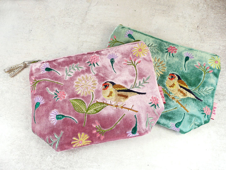 Two velvet zipped pouches with bird and floral embroidery on a light background