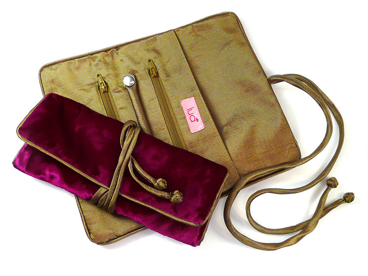 A gold-toned fabric jewelry organizer or with a matching velvet pouch in deep magenta, shown on a white background. The gold pouch has a zipper, a small pink tag with the brand name &