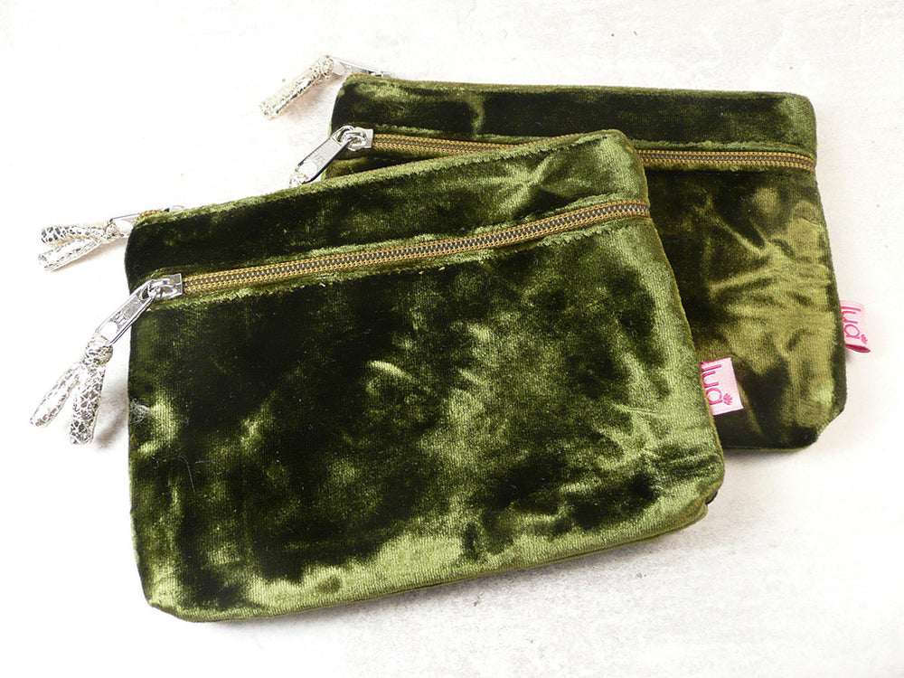 Two olive green velvet zippered pouches with silver-tone hardware and decorative zipper pulls, displayed on a light off-white background.