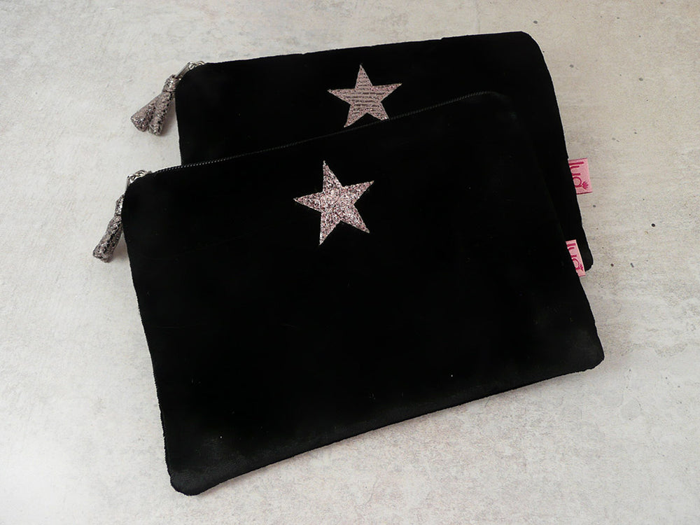 Two black velvet zippered pouches with glittery star embellishments, displayed on a light textured surface.