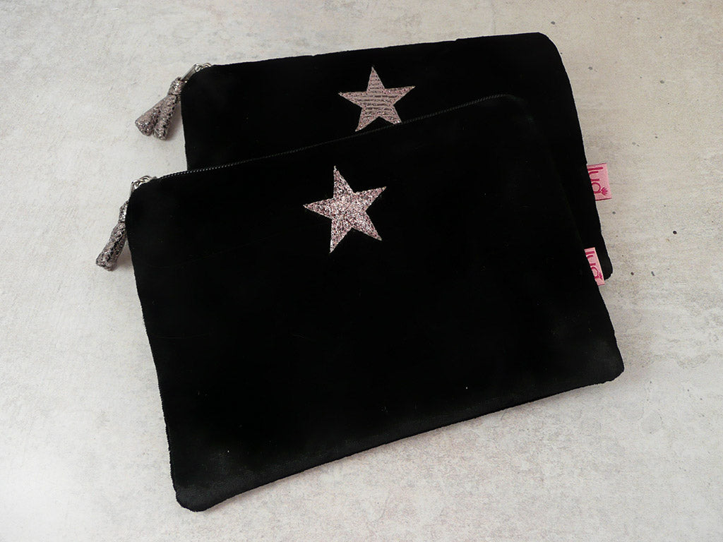 Two black velvet zippered pouches with glittery star embellishments, displayed on a light textured surface.