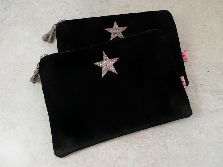 Two black velvet zippered pouches with glittery star embellishments, displayed on a light textured surface.