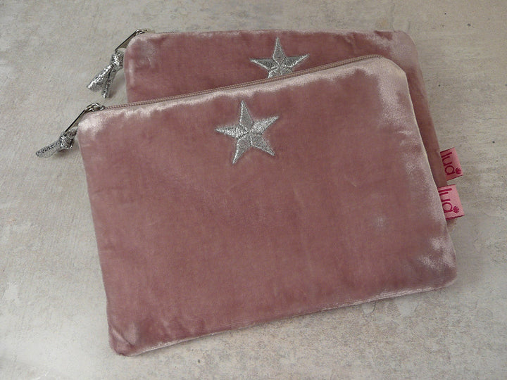 Two dusty rose velvet zippered pouches with silver star embroidery, displayed on a light grey textured surface.