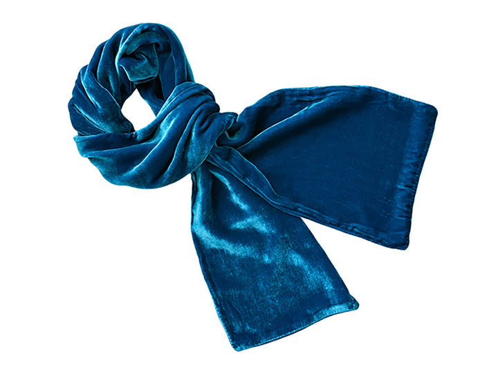 A bright blue velvet scarf, knotted and draped to show its soft texture, isolated on a solid white background.