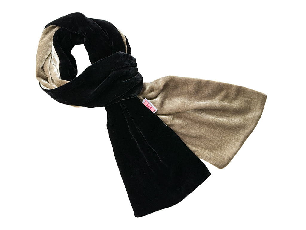 A plush velvet scarf in black and tan, draped on a white surface.
