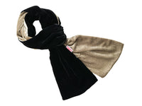 A plush velvet scarf in black and tan, draped on a white surface.